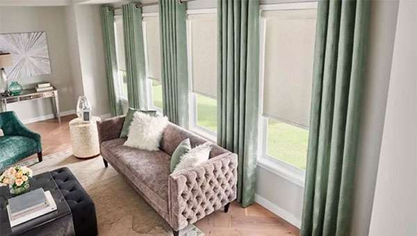 Four large living room windows with custom green draperies.