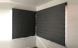 residential beach house corner windows black ribbed roman shades closed